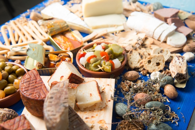 table set with an aperitif consisting of different foods cheeses and cans of pickles