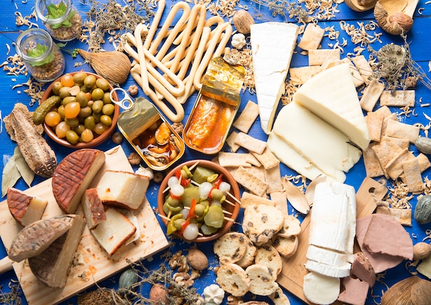 table set with an aperitif consisting of different foods cheeses and cans of pickles