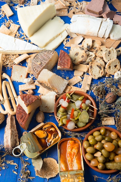 table set with an aperitif consisting of different foods cheeses and cans of pickles