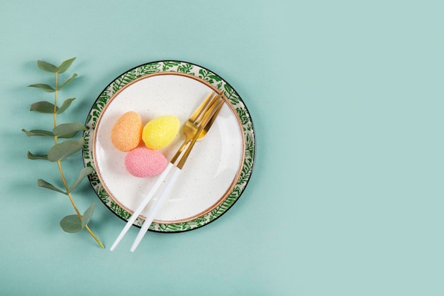 Table setting for celebrating easter plates cutlery colored eggs and eucalyptus branch on the table