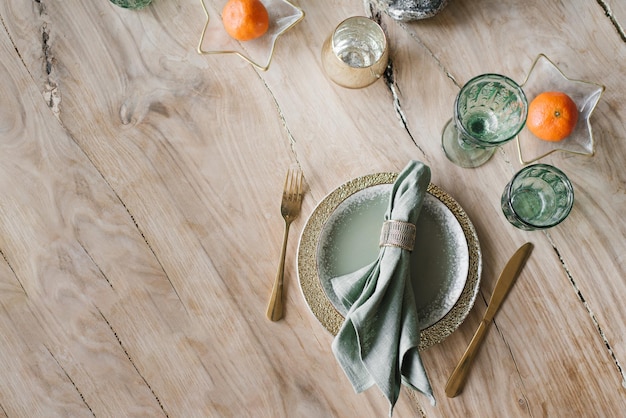 Table setting for New Year or Christmas Plates cutlery wine glasses tangerines on wood table