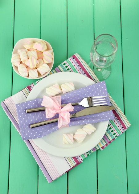 Table setting in violet and white tones on color wooden background