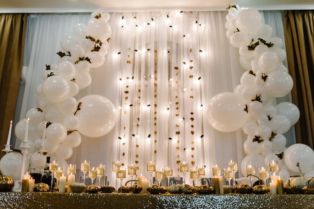 Table setting for wedding Decorated arch for wedding ceremony White balloons candles autumn leaves and small pumpkins Autumn location and Halloween decor