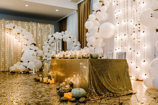 Table setting for wedding Decorated arch for wedding ceremony White balloons candles autumn leaves and small pumpkins Autumn location and Halloween decor