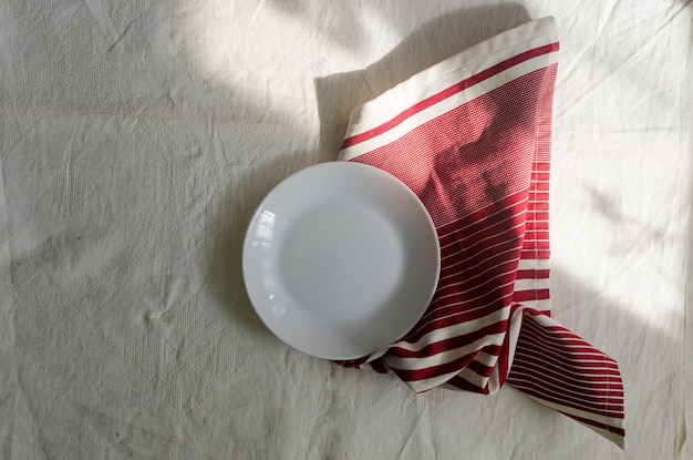 Table setting with empty white plate and linen napkin