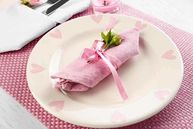 Table setting with plates, cutlery, napkin and candles on pink background