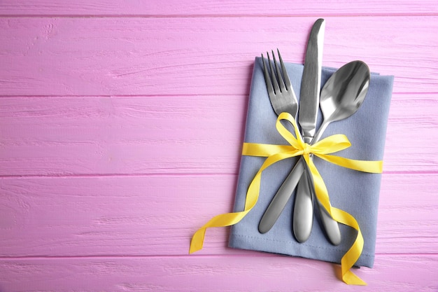 Table setting with silver cutlery and napkin on pink wooden background