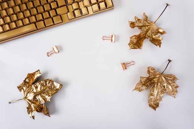 On the table there is a golden keyboard, golden maple leaves and a notebook