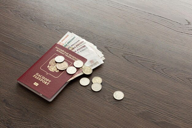 On the table there is a Russian passport inside various Russian ruble bills and small change