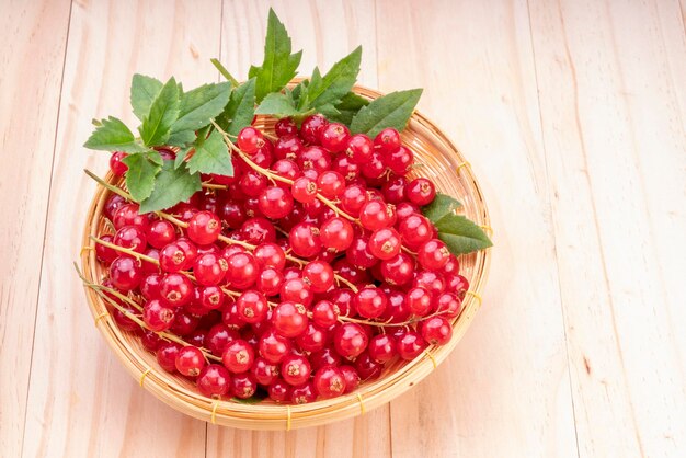 Table top view bunch of red currant in basket Red currant berries with leaf on wooden table