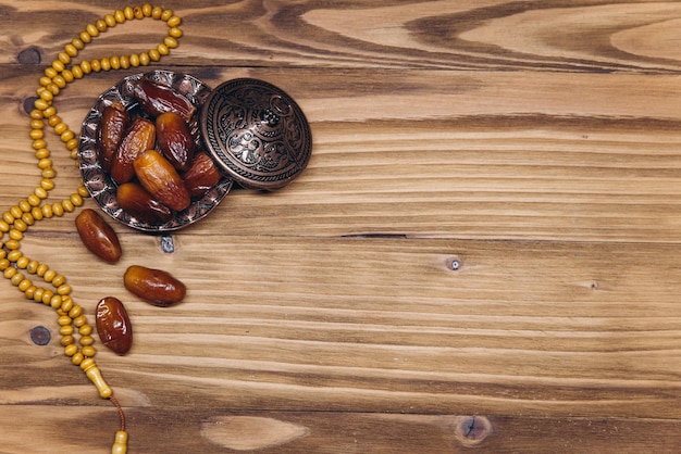 Table top view image of decoration Ramadan Kareem dates fruit and rosary beads on wooden background Flat lay with copy space