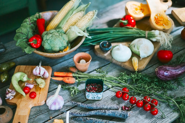 Table on veranda of country village house with different vegetables ecofriendly food from garden autumn harvesting corn pepper tomatoes cucumbers kohlrabi cabbage