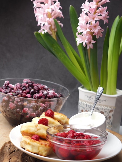 A table with a bowl of food and a flower with a pink hyacinth in the background.