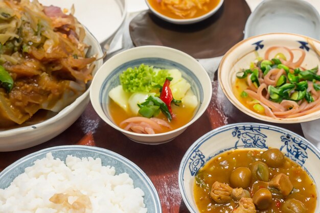 a table with bowls of food including rice rice and meat