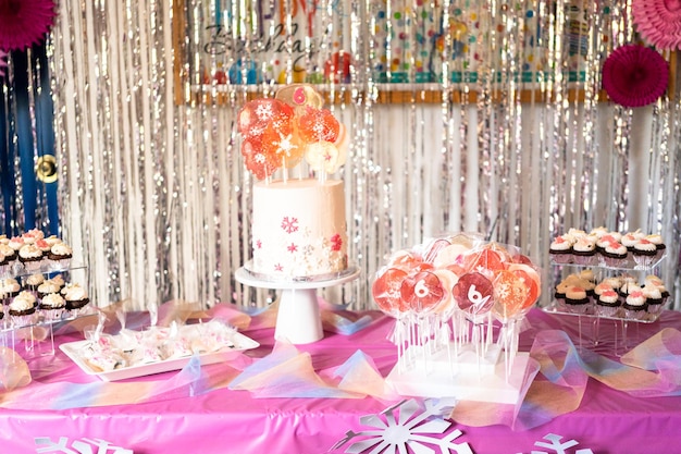 Table with cake and desserts at the little girl's birthday party.