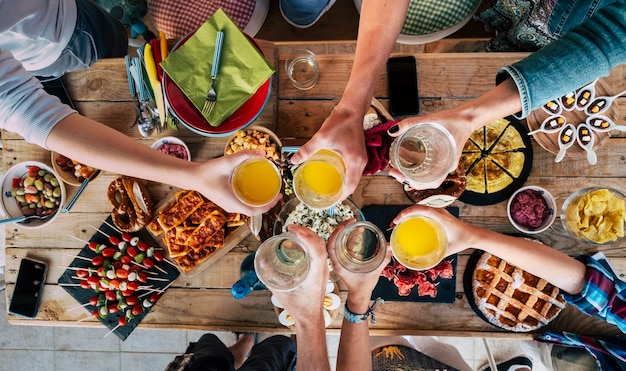 Table with food and friends clinking and toasting together in friendship having fun and celebrate