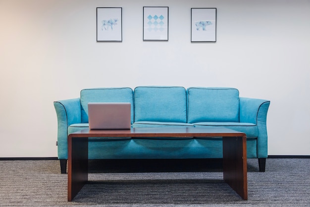 Table with laptop sofa standing in room