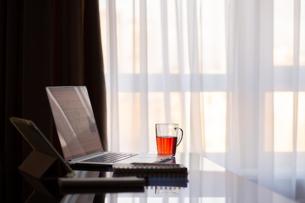 Table with laptop and tea Workplace from home Work at the home table during the war Work table by