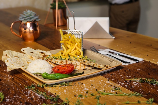 A table with a plate of food and a glass of french fries