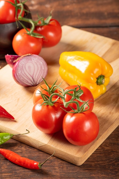 Table with red and yellow peppers peppers onions and garlic and tomatoes over rustic wood black background selective focus