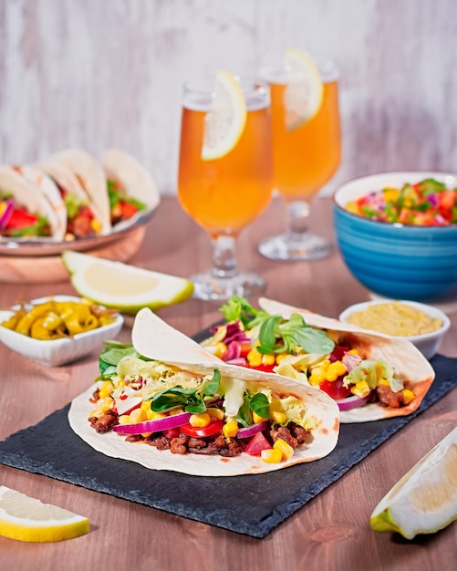 Table with tacos mango salsa nachos with sauce guacamole lemon beer for Cinco de Mayo celebration party Appetizers and traditional mexican dishes for family dinner on wooden table top copy space