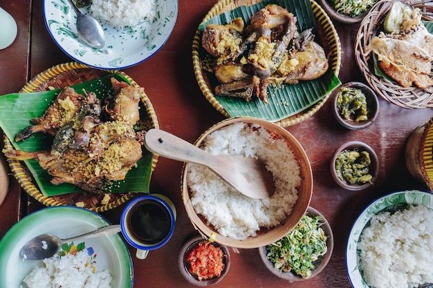 Photo a table with a variety of asian food including rice meat and vegetables set with plates bowls and utensils