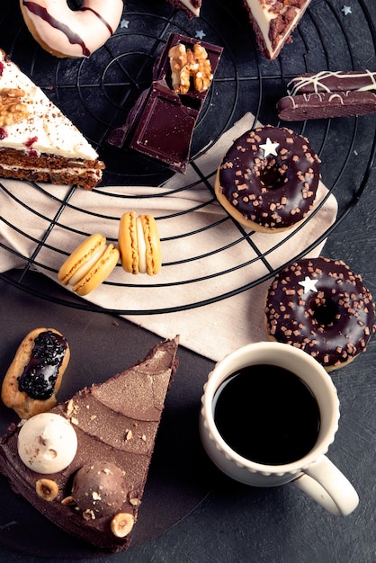 Table with various cookies donuts cakes cheesecakes on dark background Delicious dessert table Top view flat lay