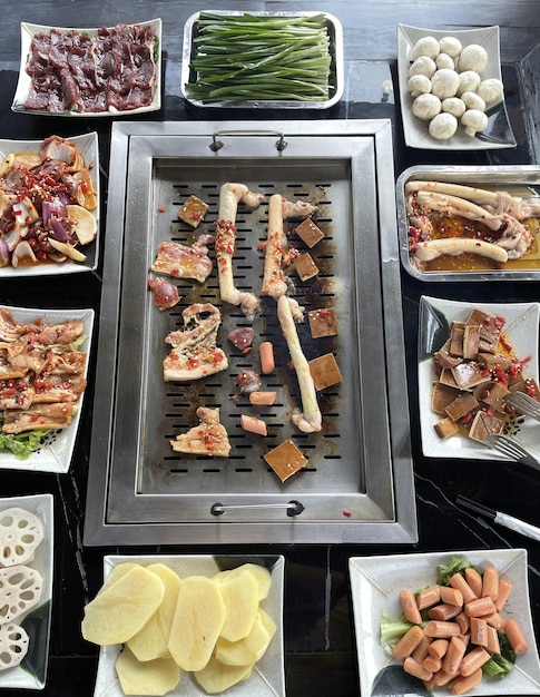 A table with various food including a grill, including a variety of meats, including a variety of vegetables and meats.