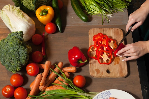 At the table with vegetables red pepper is cuted into rings