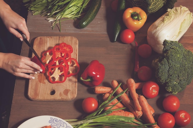 At the table with vegetables red pepper is cuted into rings