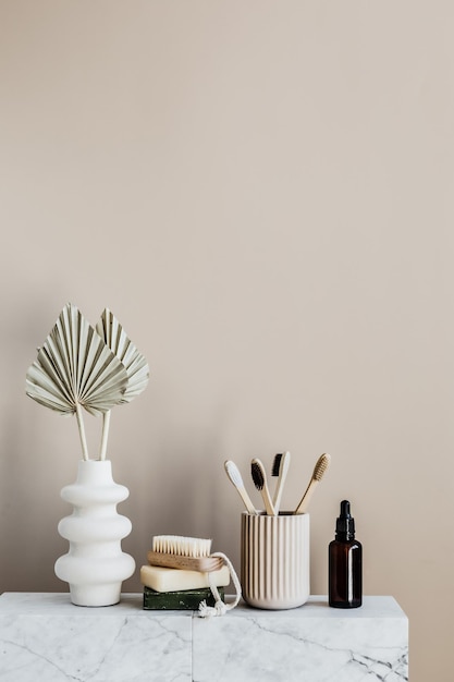 A table with a white vase, a bottle of makeup, and a brush on it.