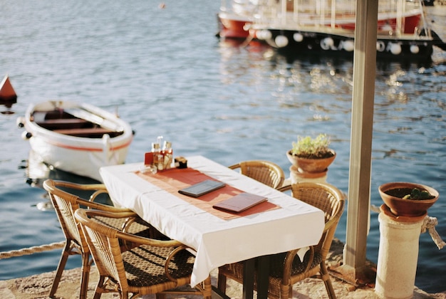 Table with wicker chairs on the pier near moored boats