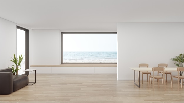 Table on wooden floor of large dining room near living area and sofa in modern beach house or luxury hotel.