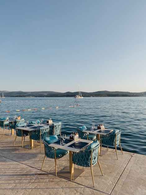 Tables with chairs in a street cafe stand on a pier by the sea