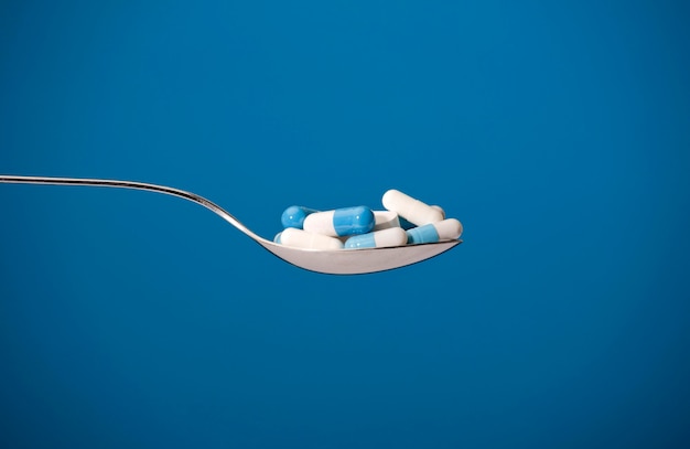 A tablespoon of white and blue tablets, blue background