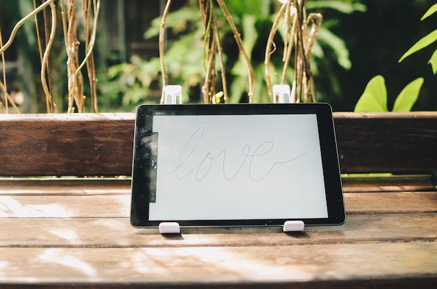 Tablet computer that says Love on a wooden table outdoors