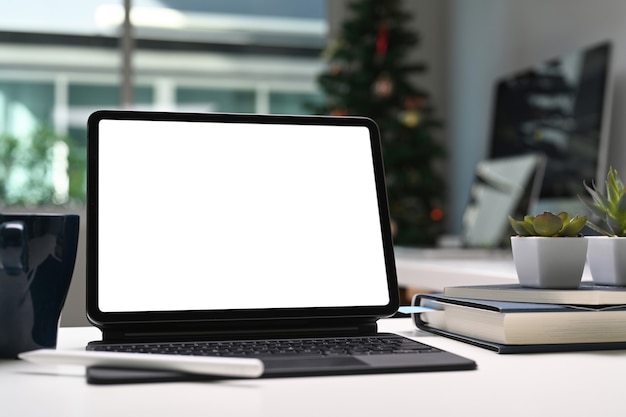 Tablet computer with blank screen, coffee cup and notebook on creative workspace.