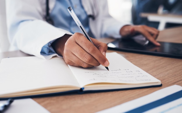 Photo tablet hands and doctor writing in book on table research and planning in hospital technology notebook and medical professional closeup at desk for information healthcare journal and telehealth