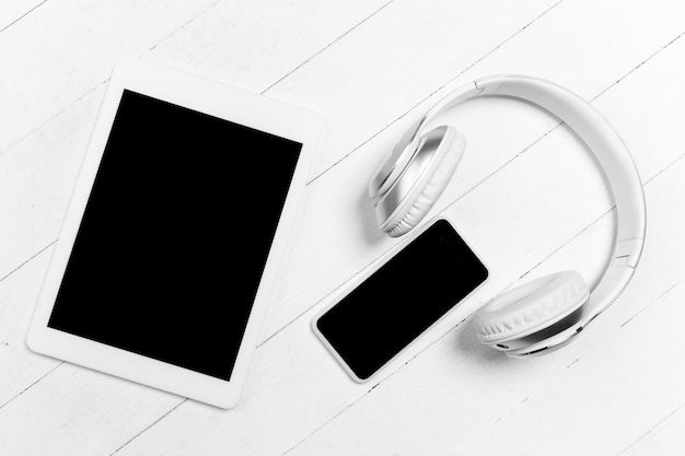 Tablet and headphones. Blank screen. Monochrome stylish and trendy composition in white color on wall. Top view, flat lay