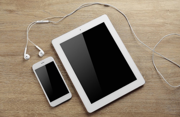 Tablet smartphone and earphones on a table close up