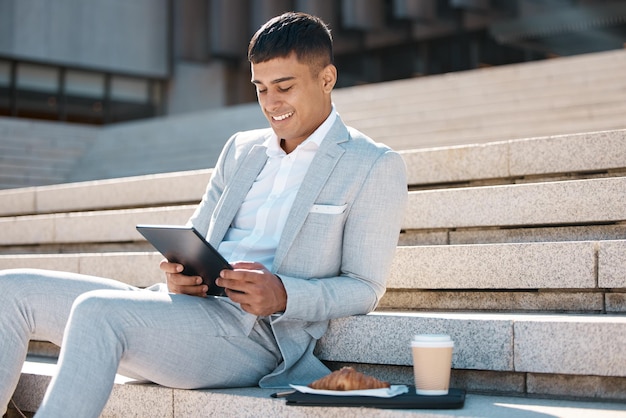 Tablet stairs and business man on coffee break reading news corporate email or give feedback on social media app Breakfast croissant lunch time or relax trading expert review stock market data