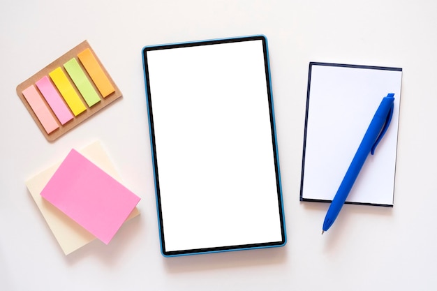 Tablet with copy space mockup on light beige background stationery stickers notebook blue pen around