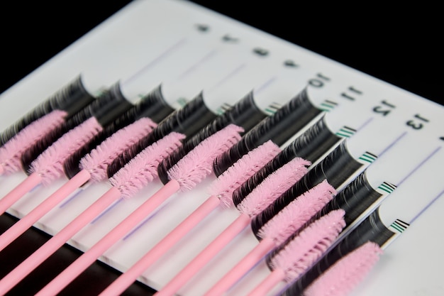 A tablet with false eyelashes and brushes on a black background Cosmetic accessories for eyelash extensions