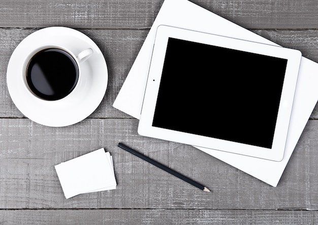 Tablet with pencil, paper cards and coffee on office desk