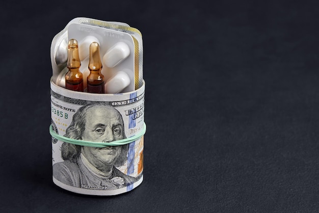 Tablets and ampoules in a blister pack are wrapped in one hundred dollar bills of money