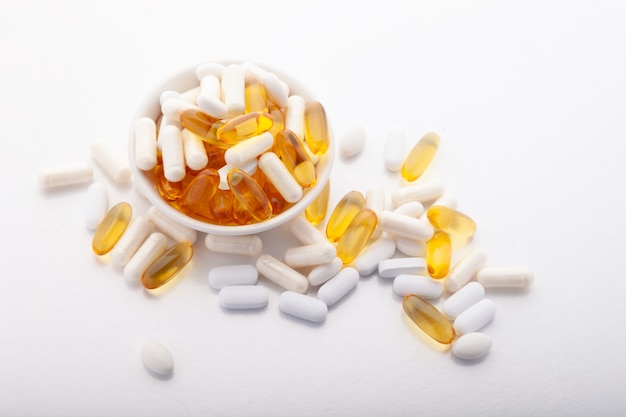 Tablets, pills, capsules, softgel on white background in bowl on white background