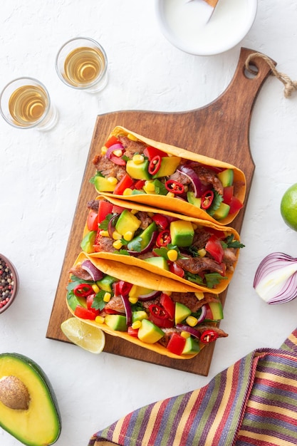 Tacos with pork, avocado, tomatoes, corn and onions. Mexican food.