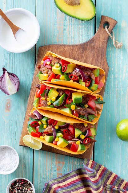 Tacos with pork, avocado, tomatoes, corn and onions. Mexican food.