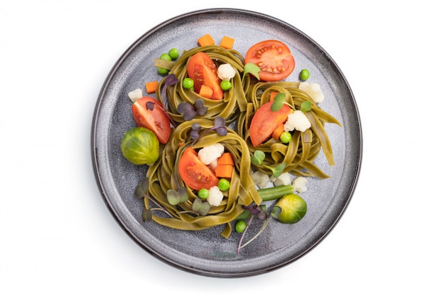 Tagliatelle green spinach pasta with tomato, pea and microgreen sprouts isolated on white background. Top view.