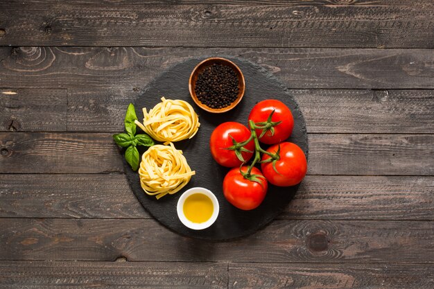 Tagliatelle with tomato and basil, made at home, on a wooden background.